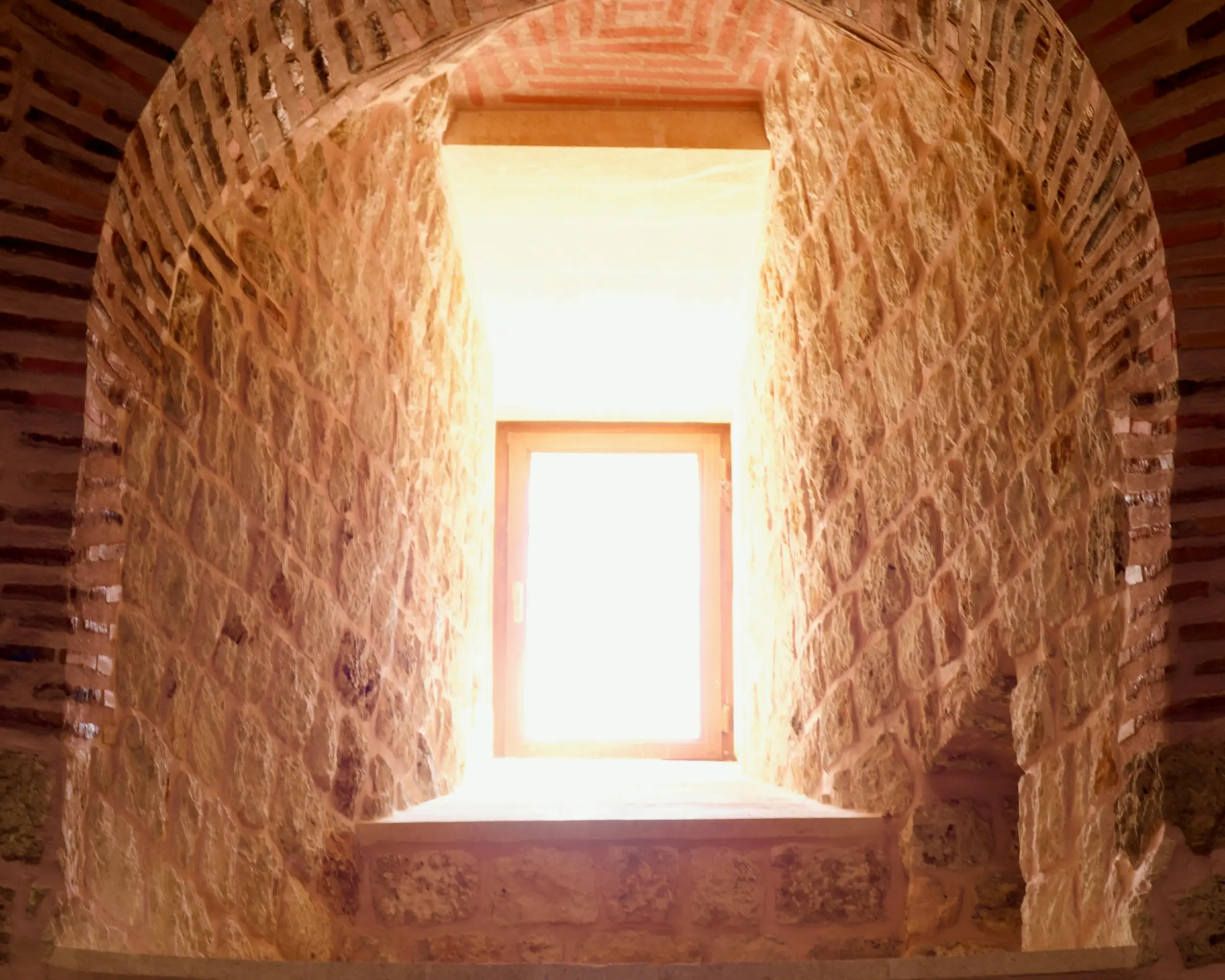 Lumière qui traverse une fenêtre percée dans un mur épais, enduit à la chaux.